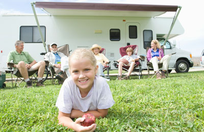 Girl enjoying an apple on a camping holiday with family